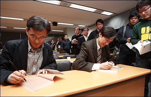 오연호 <오마이뉴스> 대표와 조국 교수가 참석자들의 책에 사인을 해주고 있다.
