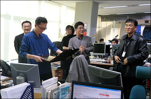 오마이뉴스 동료들이 마련한 동판을 들고 기뻐하는 성낙선 기자(왼쪽 두번째)