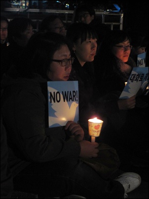 29일 보신각 앞에서 열린 '평화기도회'에서 한 시민이 'NO WAR'라고 적인 손팻말을 들고 촛불을 밝히고 있다. 