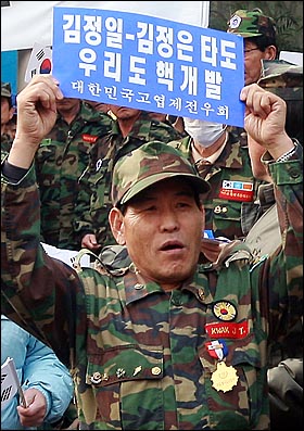 고엽제 전우회 회원이 '김정일-김정은 타도, 우리도 핵개발'라고 적힌 손피켓을 들어보이고 있다.
