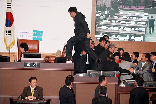 1일 밤 '친환경무상급식 조례안' 처리에 대한 민주당과 한나라당의 협상이 최종결렬된 가운데, 김형식 민주당 서울시의원이 의장석을 에워싸고 있는 한나라당 의원들을 피해 의장석으로 달려가고 있다.