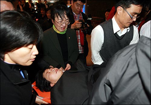 8일 오후 한나라당이 2011년 예산안을 강행처리하기 위해 야당의원들이 점거한 국회 본회의장 의장석에서 야당의원들을 끌어내는 과정에서 이정희 민주노동당 대표가 실신해 들것에 실려 나가고 있다.