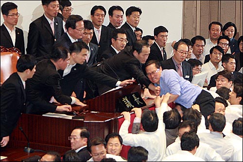 2010년 12월 8일 오후 서울 여의도 국회 본회의장에서 정의화 국회부의장이 2011년 예산안을 강행처리를 시도하자, 홍영표 민주당 의원이 예산안 표결 처리를 막기 위해 의장석으로 뛰어오르고 있다.