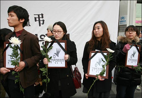 기자회견 참가자들이 '국가인권위원회 사망'을 상징하는 영정사진과 국화꽃을 들고 있다.