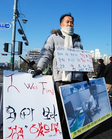 삼성전자 해고 노동자 박종태씨가 삼성전자 수원사업장 중앙문 앞에서 1인 시위를 하고 있다. 푯말에는 I was fired(나는 해고당했다)라는 영어 문구가 적혀있다.