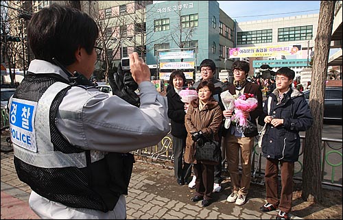 9일 오전 서울 영등포구 여의도고등학교에서 열린 졸업식에서 한 경찰관이 졸업생 가족의 기념사진을 찍어주고 있다.
