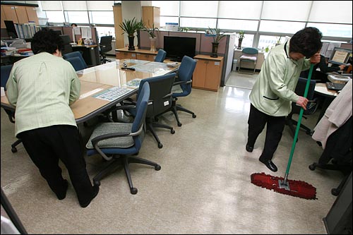 성동구청 청소용역 여성노동자들이 구청 사무실 테이블과 바닥을 청소하고 있다.