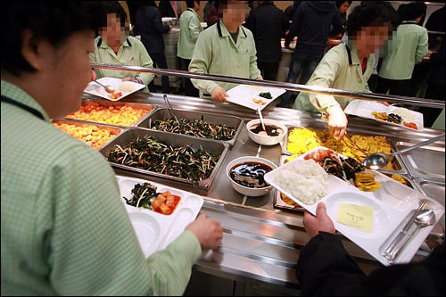 성동구청 청소용역 노동자들이 지하 1층 구내식당에서 일반직원들과 함께 점심식사를 위해 식판에 음식을 담고 있다.