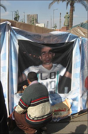 12일(현지 시각) 이집트 수도 카이로의 타흐리르 광장에서 한 시민이 무바라크 퇴진 요구 시위 중 희생된 이의 사진을 새겨 넣은 천막에 글을 적고 있다.