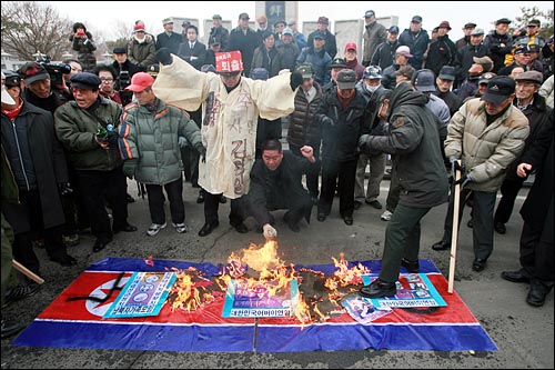 대북전단을 날려보낸 어버이연합 회원들이 김일성, 김정일, 김정은 사진과 인공기를 불태우고 있다.