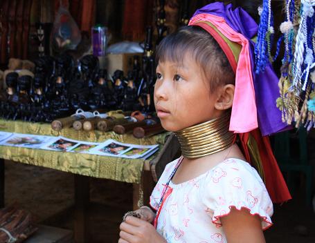 어린 아이가 목에 링을 하고 기념품을 팔고 있다.  