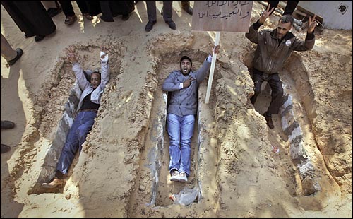 리비아 수도 트리폴리 인근 자위야의 광장 공원에서 지난 2월 27일 시민들이 최근 시위 중 희생된 이들을 위해 마련된 무덤 옆에 땅을 파고 누워 죽음도 불사하겠다는 각오를 나타내고 있다.