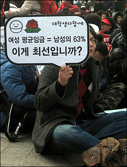 5일 서울광장에서 열린 '대학 비정규직 노동자 파업 승리 결의대회'에서 한 참가자가 여성 노동자의 열악한 처우 문제를 비판하는 피켓을 들고 있다.