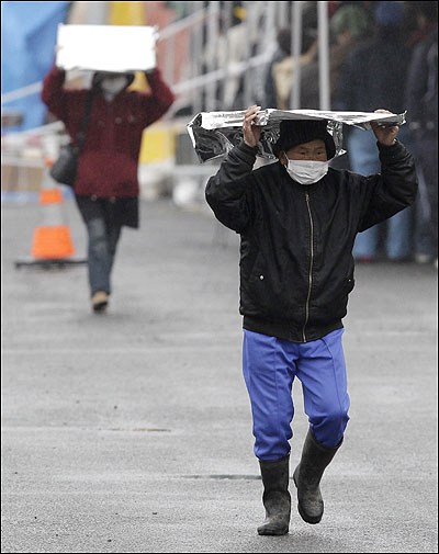 지난 15일 일본 후쿠시마현의 코리야마시의 한 주민이 담요를 쓰고 방사선긴급검사소를 나서고 있다. 