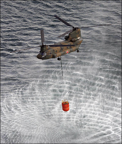 17일 오전(현지시각) 일본 동북부 해상에서 자위대 헬기가 후쿠시마(福島)현 제1원자력발전소를 냉각시키기 위해 쏟아부을 바닷물을 퍼올리고 있다.
