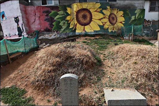 벽화앞에 놓인 묘지는 벗어날 수 없는 동반자다. 