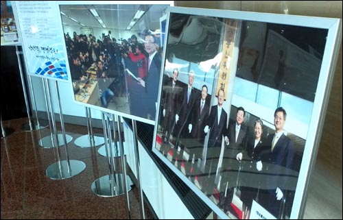 25일 방통위 로비에 전시된 사진들. 지난해 12월 31일 최시중 위원장이 종편 사업자를 발표하는 장면(가운데)과 2008년 방통위 1기 출범 당시 사진(오른쪽)이 나란히 전시돼 있다.