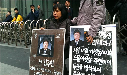 삼성전자 서초 사옥 앞에서 고 김주현씨의 어머니와 누나가 피켓을 들고 있다. 뒤에는 보안요원이 건물 출입을 막고 있다.