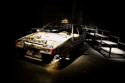 연극 < TAXI, TAXI>의 무대 위에 택시 한 대가 놓여 있다.