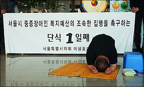 13일 오후 서울 중구 서소문동 다산플라자 로비에서 장애인 복지예산 집행을 촉구하며 이상호 서울시의회 의원이 108배를 하고 있다.