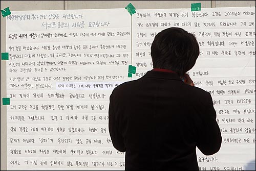 13일 오후 대전 유성구 카이스트 교정에서 한 학생이 서남표 카이스트 총장의 사퇴를 촉구하는 대자보를 읽고 있다.