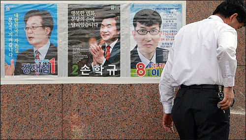 4·27 재보궐 선거를 사흘 앞두고 24일 경기도 성남시 분당을에 출마한 여야 후보들의 선거벽보 앞을 한 주민이 지나고 있다.