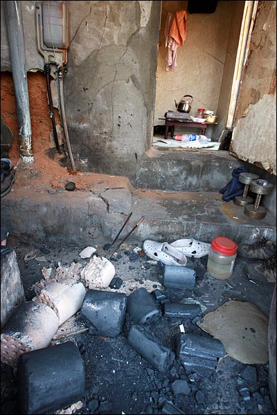 사람이 살고 있는 집 벽을 철거반원이 부수면서 연탄 조각이 나뒹굴고 있다.