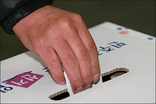 4.27 재보궐 선거일인 27일 오전 비가 오는 궂은 날씨에도 투표소를 찾은 한 직장인이 출근전에 투표에 참여하고 있다. 
