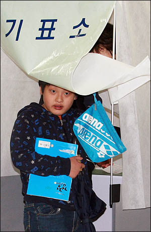 4.27 재보궐 선거일인 27일 비가 오는 궂은 날씨에도 강원도 춘천의 한 투표소를 찾은 어린이가 엄마를 따라 기표소에 들어가보고 있다.