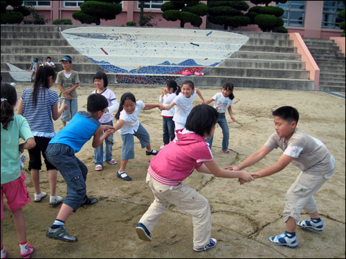 아이들이 점심시간에, 직접 만든 타일벽화 앞에서 신나는 민속놀이 체험을 하고 있다.