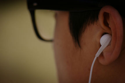 귓속형 이어폰으로 음악을 듣고 있다.
