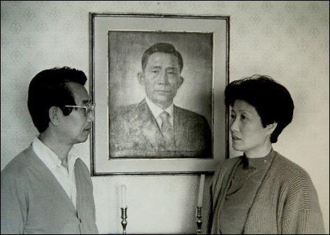 박정희 전 대통령의 맏딸인 박재옥씨와 남편 한병기씨가 박 전 대통령 사진 앞에 서 있다.