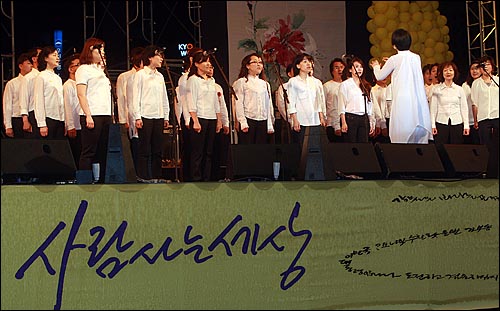 시민학교 합창단이 21일 오후 서울광장에서 열린 '파워 투 더 피플(Power To The People) 2011' 추모콘서트에서 '함께 가자 우리 이길을'을 시민들과 함께 부르고 있다.