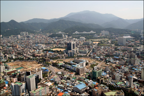 광주 시내와 무등산. 뒤로 보이는 산이 무등산. 광주 시내 중앙에 5.18 때 항쟁의 중심이 된 전남도청 앞 분수대가 보인다. 그 왼쪽에 보이는 공터에 참여정부 때 건설을 시작한 '아시아문화전당'을 짓고 있다.