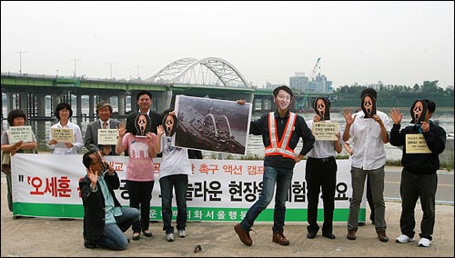 한강운하백지화서울행동 소속 환경운동가들이 25일 오전 서울 양화대교 부근에서 공사장 근무복을 입은 오세훈 시장의 아찔한 'S'라인(양화대교 개조 공사)에 시민들이 경악하는 모습을 담은 퍼포먼스를 벌이고 있다.