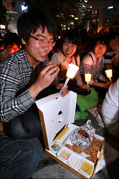 '반값등록금' 실현을 위한 촛불집회가 3일 오후 서울 광화문 KT앞에서 열린 가운데 대학생들을 지지하는 '날라리 선배부대'(트위터리안 모임), '쌍코' '쏘울드레스', 네티즌들이 배달시킨 치킨을 학생들이 맛있게 먹고 있다.