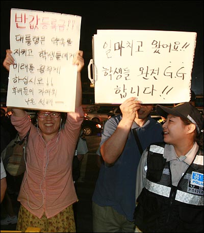 '반값등록금' 실현을 위한 대학생 촛불집회가 3일 오후 서울 광화문 KT앞에서 열리는 가운데, 시민들이 대학생들을 격려하는 글을 적어서 폴리스라인 밖에서 들고 있다. 시민들이 들고 있는 종이에는 "반값등록금!! 대통령은 약속을 지키고 학생들에게 미래를 꿈꾸게 하십시오!! 후배들이 가여워 나온 선배" "일 마치고 왔어요!! 학생들 완전 G.G합니다!!"라는 격려의 글이 적혀 있다.