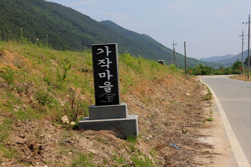 마을 입구 도로변에 놓인 가작마을 안내비