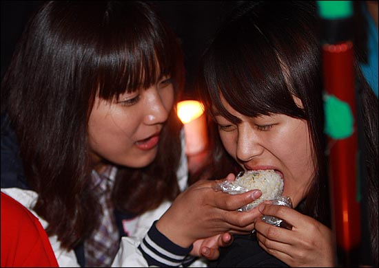7일 오후 서울 청계광장 인근 서울파이낸셜센터 앞 계단에서 열린 '반값등록금 실현을 위한 촛불집회'에 참가한 대학생들이 '주먹밥 부대'가 만들어 준 주먹밥을 서로 나눠먹고 있다.