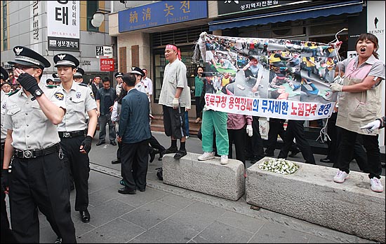  노점상 주인들이 현수막을 들어보이며 "폭력을 행사하는 용역업체 직원들을 왜 경찰들이 가만히 놔두냐"고 항의하고 있다.