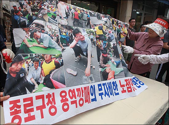  한 노점상 주인이 <오마이뉴스>의 현장사진 등으로 만든 현수막을 들어보이며 항의하고 있다.