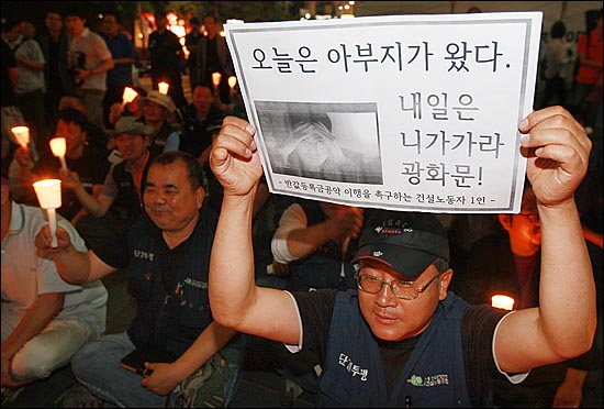 8일 오후 서울 청계광장에서 열린 '반값등록금 실현을 위한 촛불집회'에서 한 시민이 "오늘은 아부지가 왔다. 내일은 니가가라 광화문!라고 적힌 피켓을 들어보이며 반값등록금 실현을 촉구하고 있다.