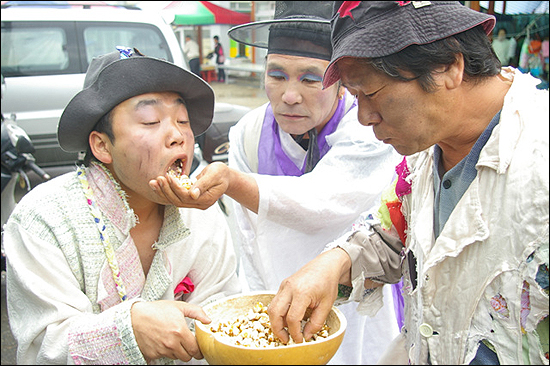 동냥바가지에 동냥해온 튀밥을 나눠 먹는 각설이패들  

