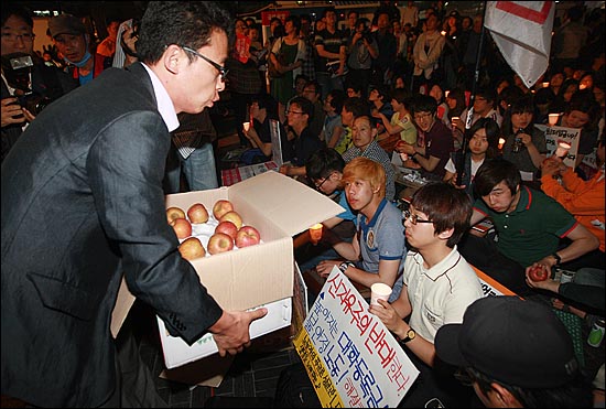 '등록금과 교육비를 걱정하는 학부모 모임' 회원들이 비싼 등록금으로 고생하는 학생들에게 '사과'한다는 뜻으로 사과를 나눠주고 있다.