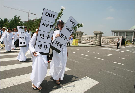 경찰의 저지로 국회 정문앞 기자회견을 포기한 가운데, 소복을 입은 여학생들이 국회꽃이 꽂힌 피켓을 들고 국회앞을 지나고 있다.