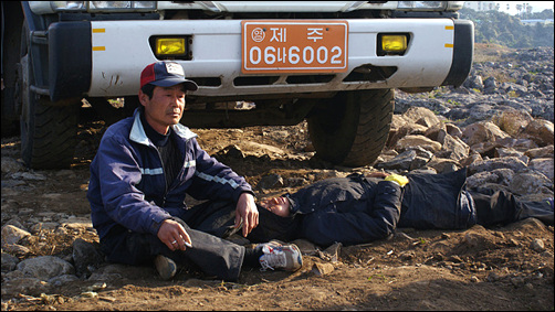 김종환씨가 트럭의 진입을 방해하기 위해 길바닥에 앉아 있다. 그 옆에 누운 사람이 구속된 최성희씨.