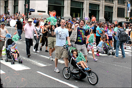 26일 뉴욕 맨해튼에서 열린 게이 퍼레이드 참가자들, 게이커플로 보이는 두 남성이 아이를 태운 유모차를 밀며 행진하고 있다. 