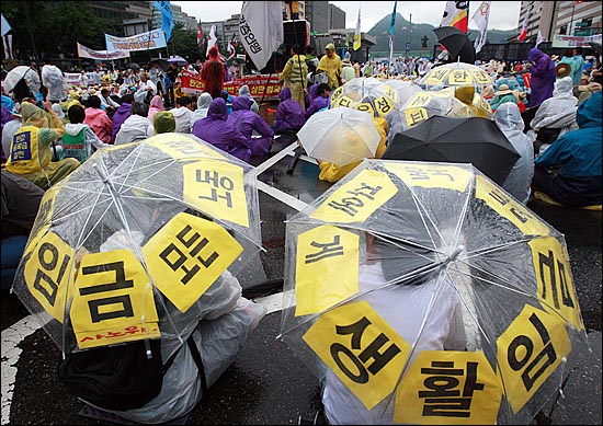 '민생파탄 이명박 정권 심판 범국민대회'에서 참가자들이 최저임금 현실화 등을 요구하는 문구를 우산에 붙이고 집회에 참가하고 있다.