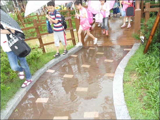 비가 올 때마다 물이 고여서 아이들이 물을 피해 다니고 있습니다.