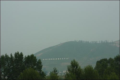 차창너머로 보이는 북한땅에 '21세기 태양 김정일 장군만세'라는 구호가 적힌 대형 간판이 보인다. 